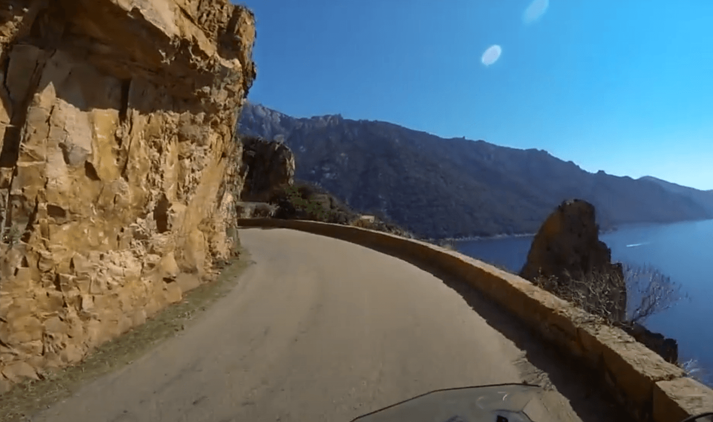 Vue depuis la selle d'une moto sur une route côtière des calanques de Corse